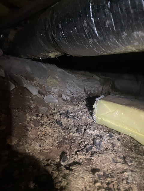 A close up of a duct in a basement with a hole in it.