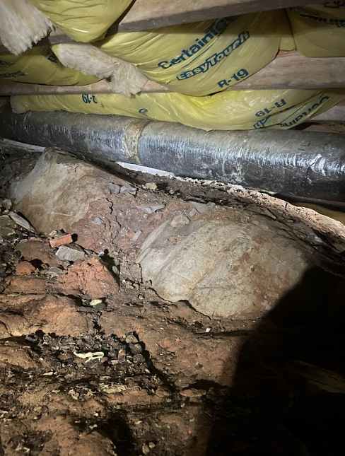A person is standing under a pipe in a basement.