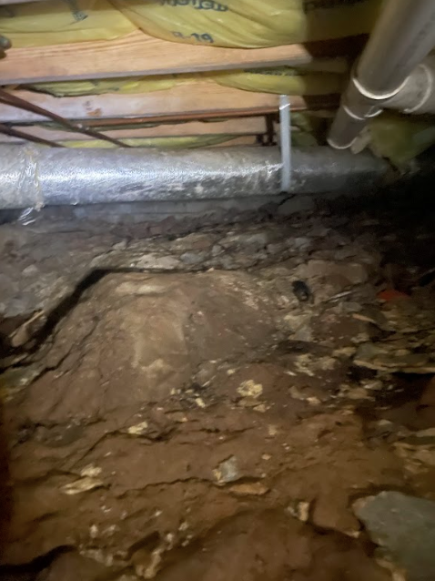 There is a pipe in the ceiling of a basement.