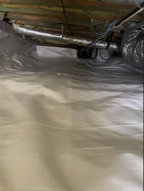 A picture of a crawl space covered in plastic.