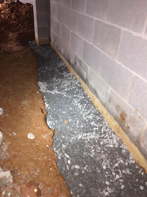 A brick wall is being built in a basement.