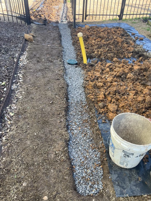 A bucket of dirt is sitting next to a pile of gravel.