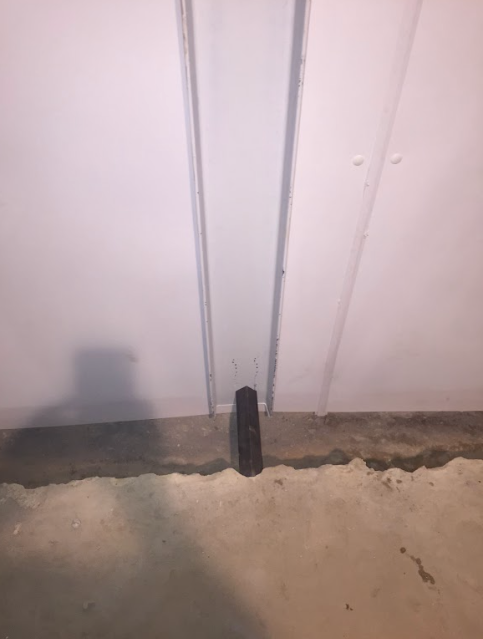 A black object is sitting on the floor next to a white wall.