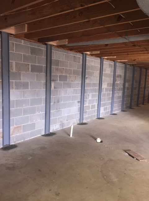 An empty basement with brick walls and a wooden ceiling.