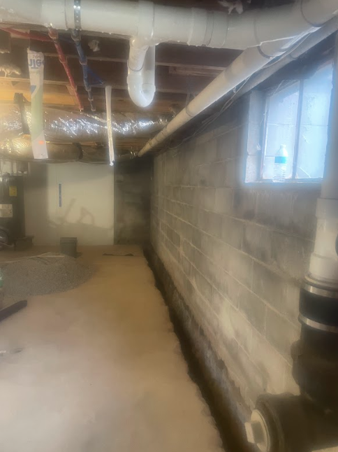 A very long hallway in a basement with a brick wall.