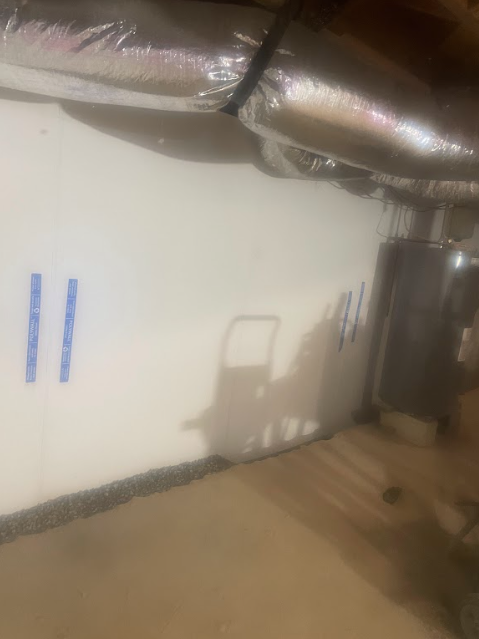 A shadow of a person is cast on a wall in a basement.