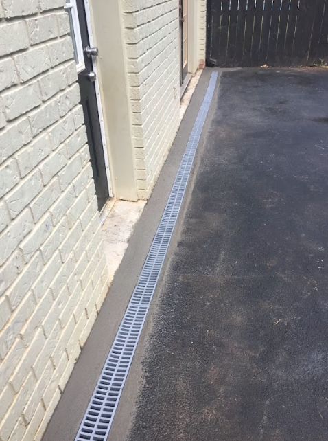 A drain on the side of a building next to a brick wall.