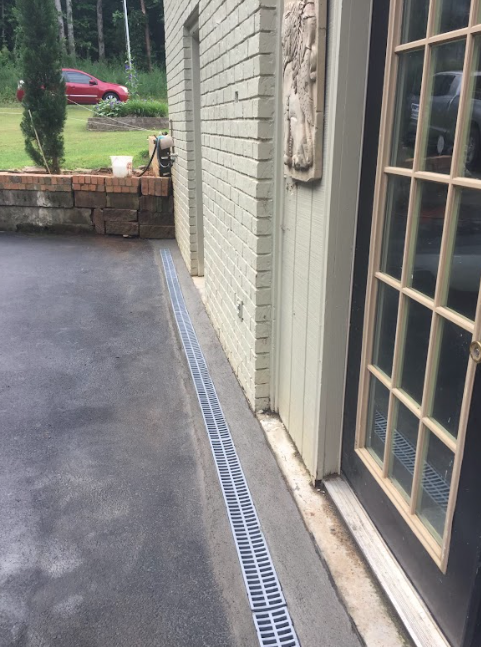 A drain on the side of a building next to a door.