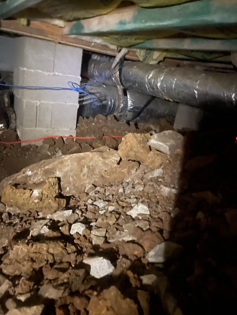 A basement with a lot of rocks and pipes coming out of it.