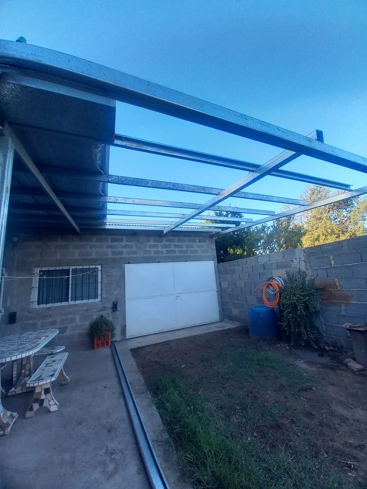 Una casa de ladrillo con techo de metal y una puerta de garaje blanca.