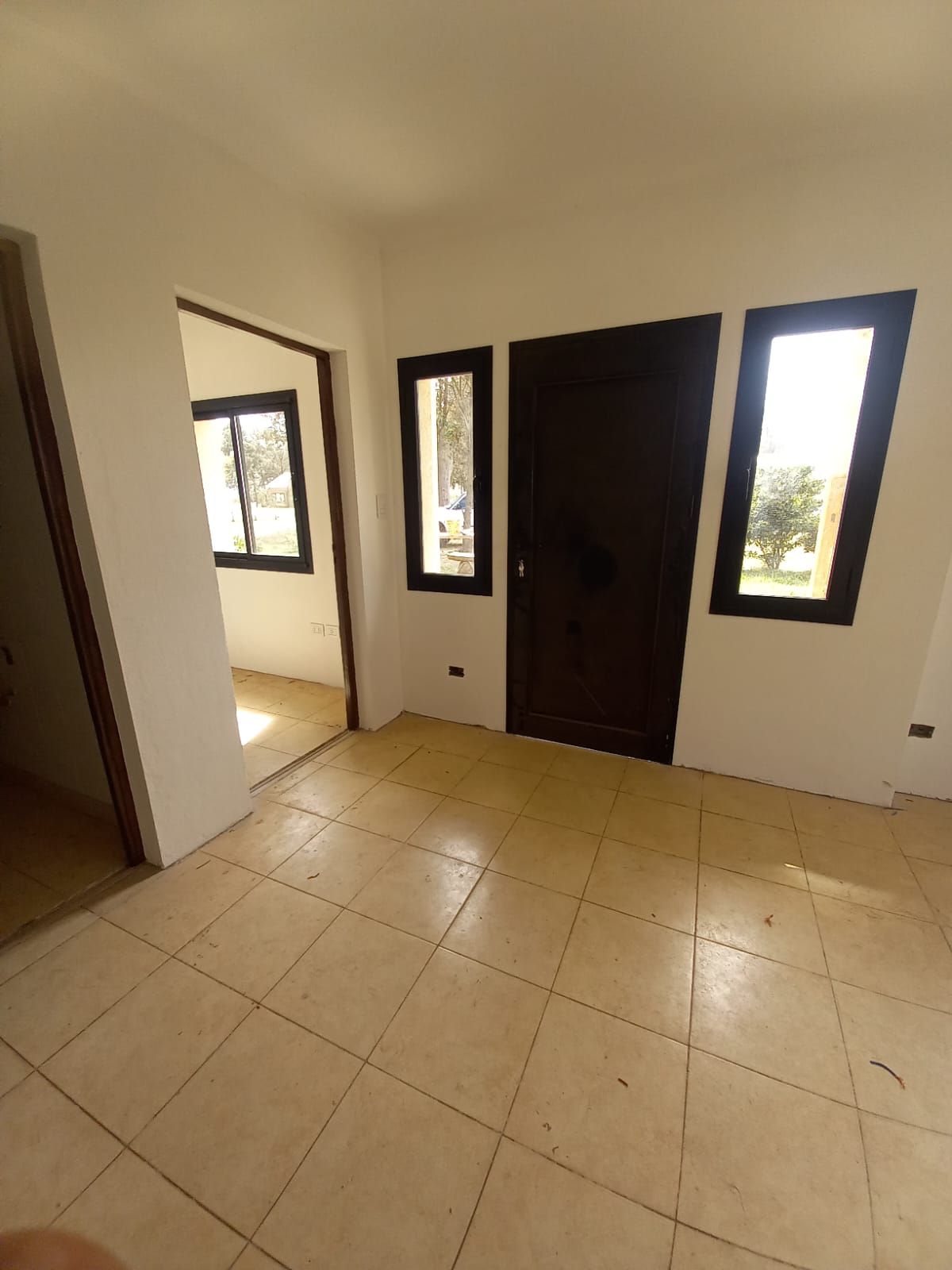 Una habitación vacía con suelo de baldosas y tres ventanas.