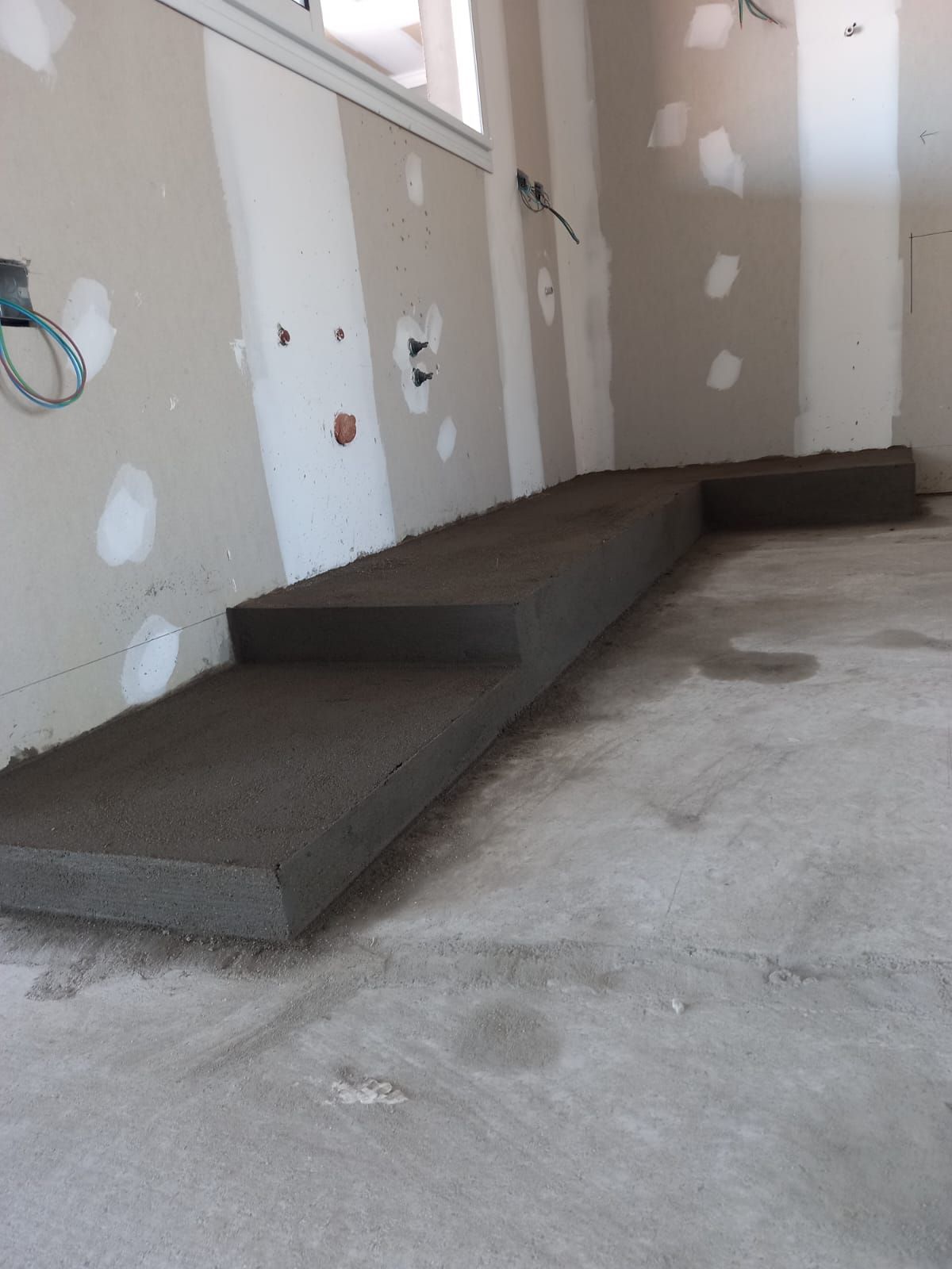 Un piso de concreto en una habitación con ventana.