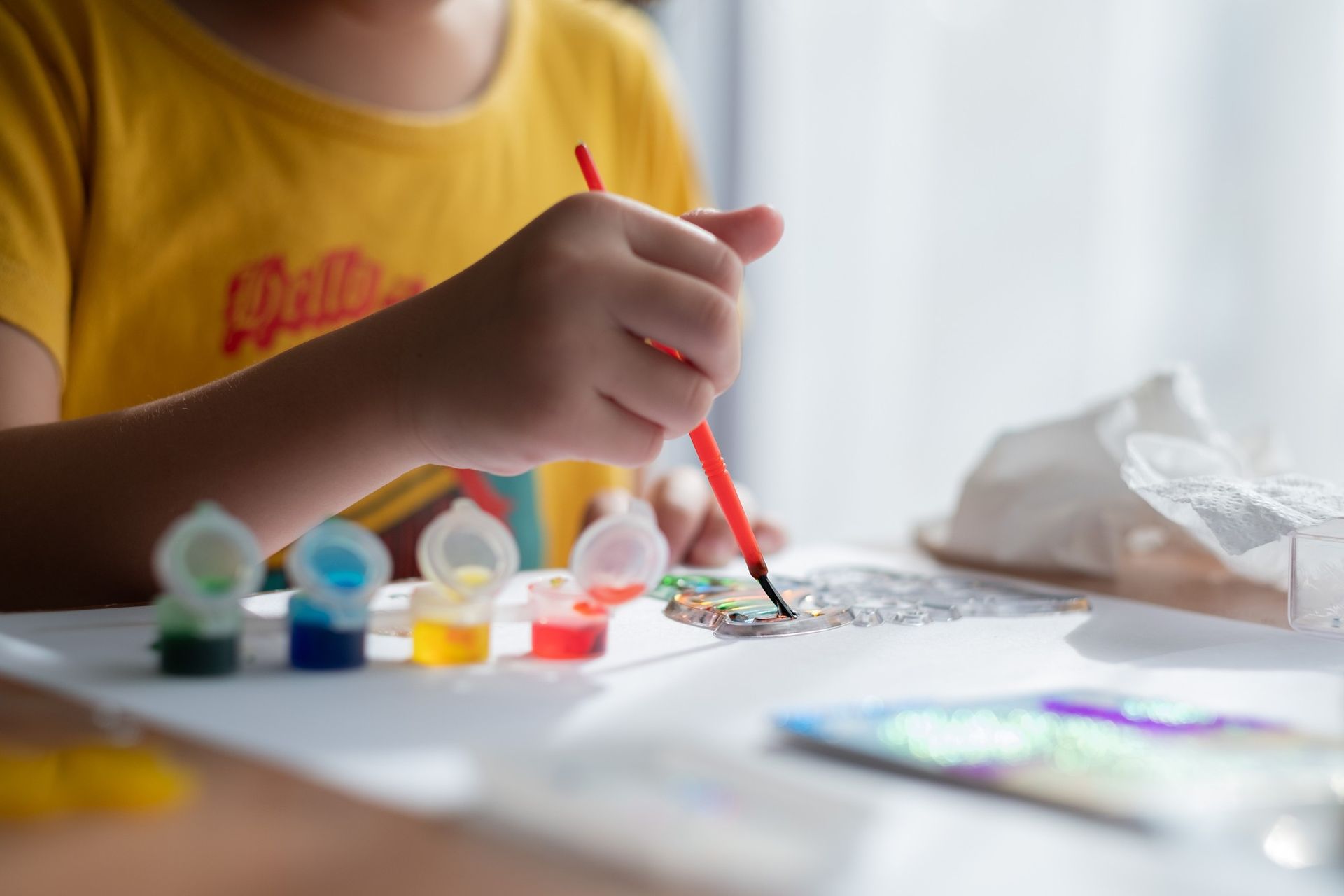 A child is painting with a brush on a piece of paper.