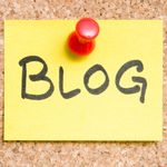 Yellow sticky note pinned to corkboard, word "BLOG" in black letters.