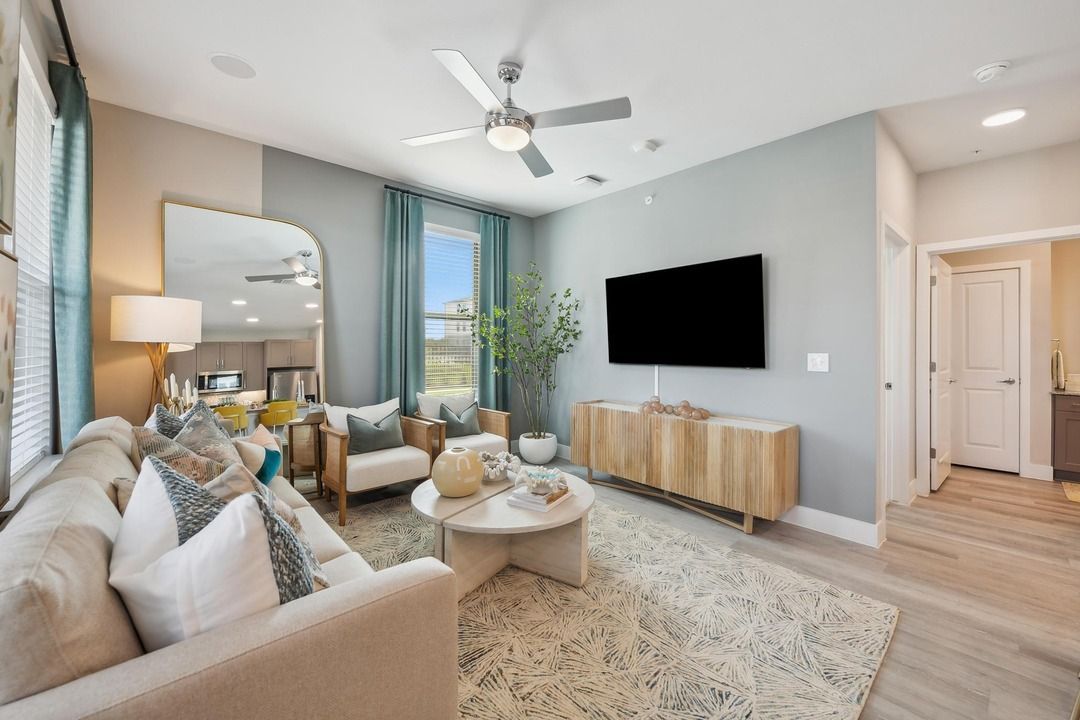 A living room with a couch , chairs , and a flat screen tv.