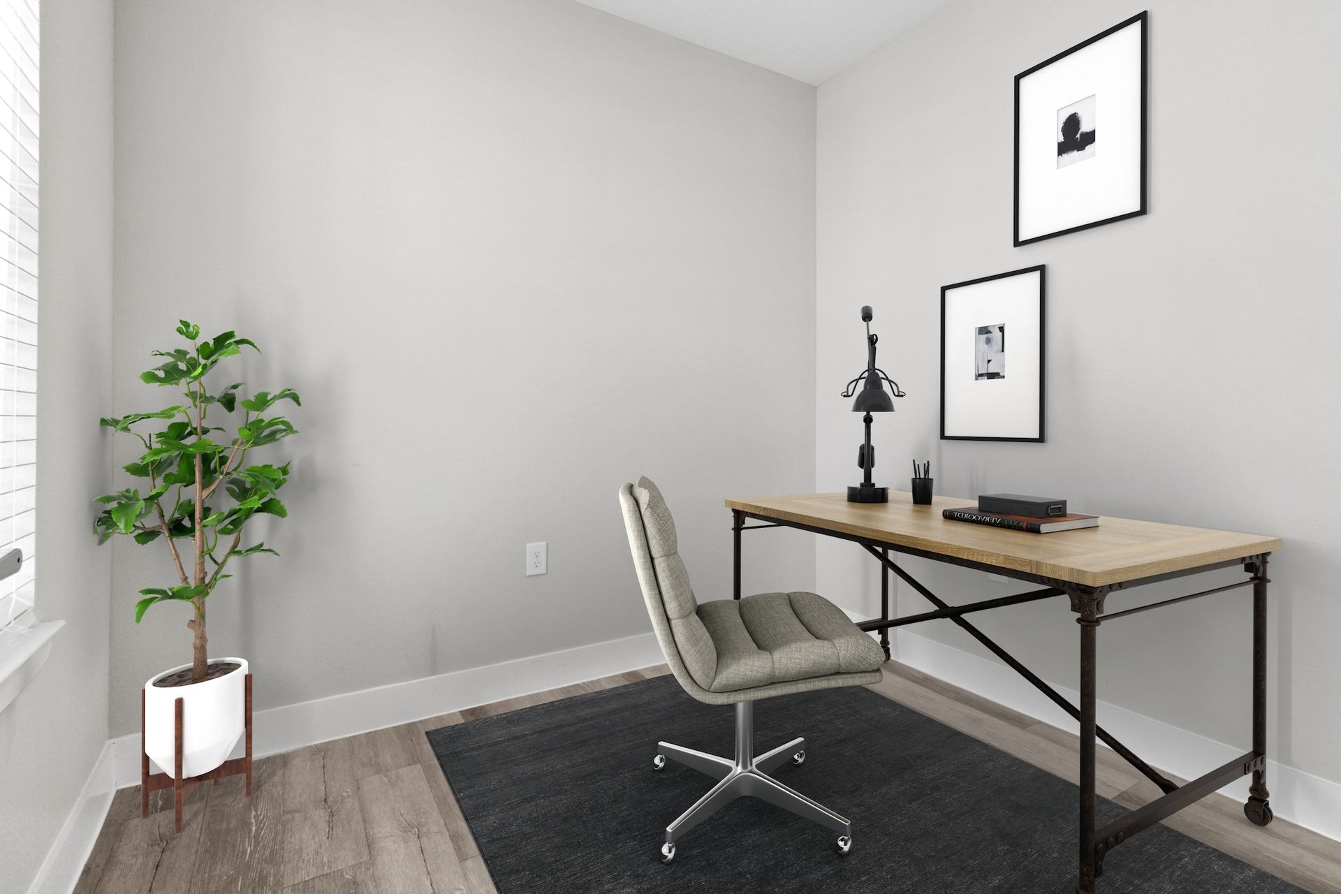 Home office with desk, chair, plant, and framed art against a light gray wall.