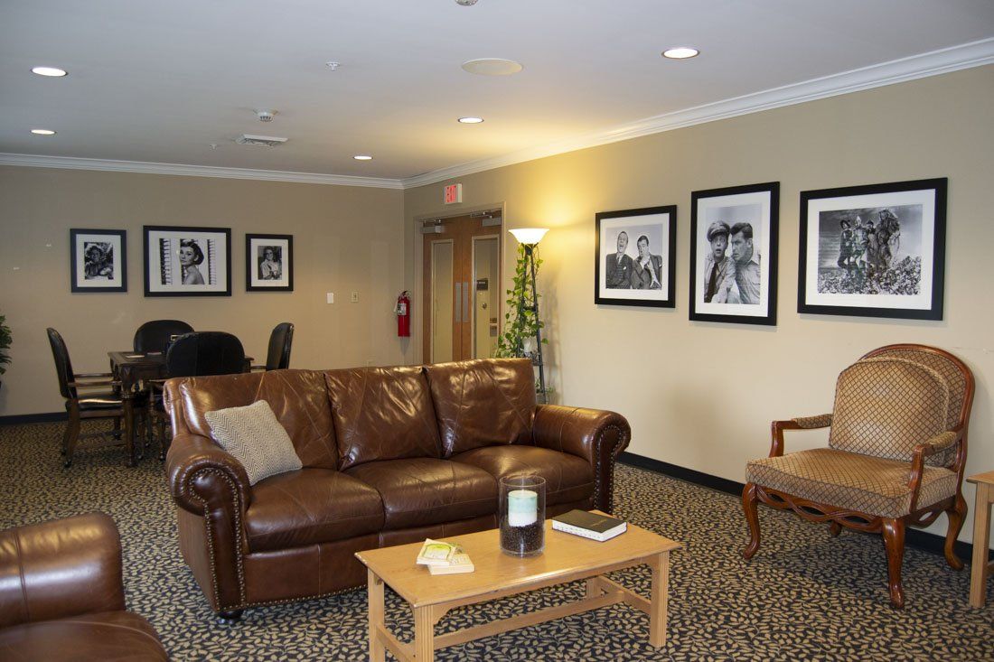 A living room with a brown leather couch and chairs