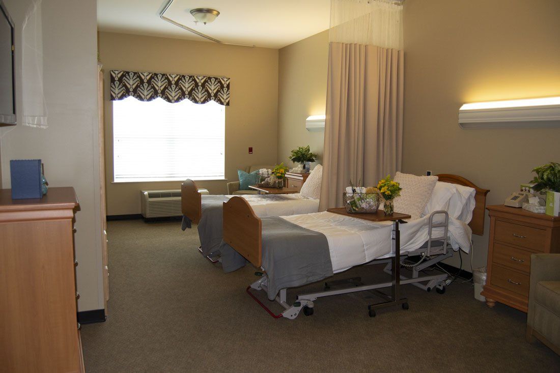 A hospital room with two beds and a window.