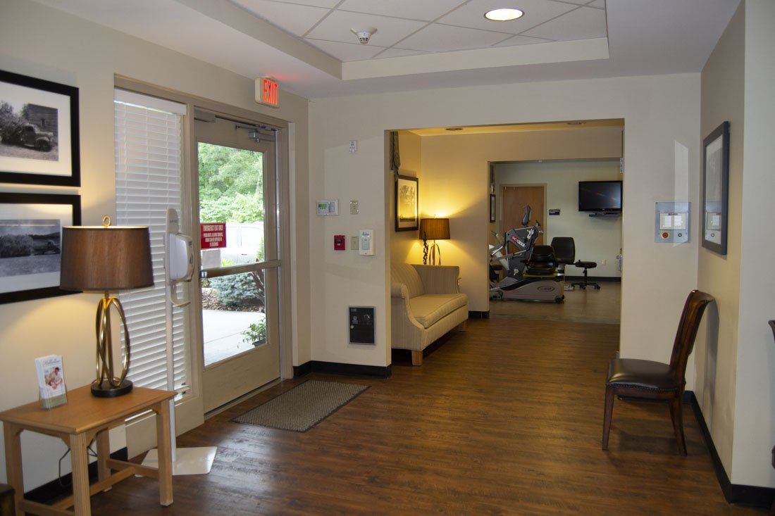 A hallway with a couch and chairs and a red exit sign