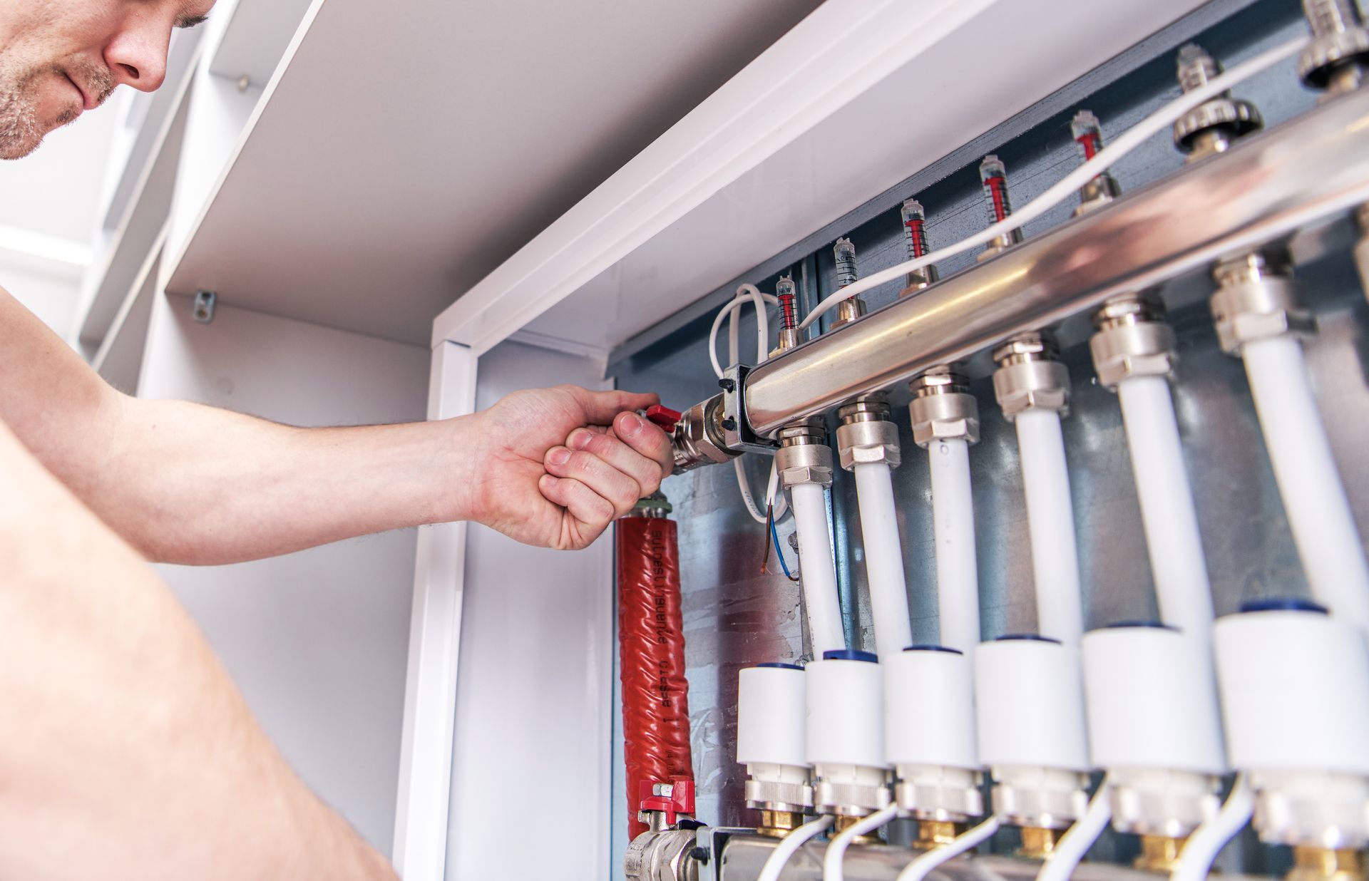 A partial view of a plumber repairing a water pipe system.