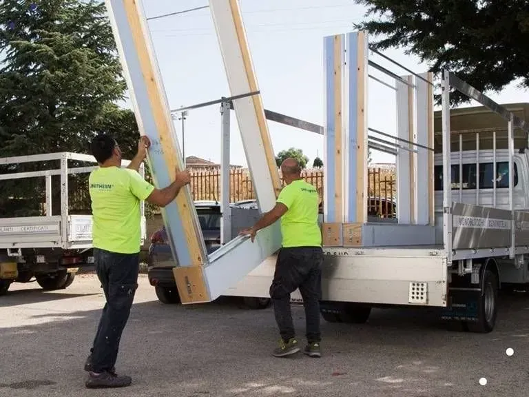 Due uomini con camicie verde neon trasportano un grosso pezzo di legno