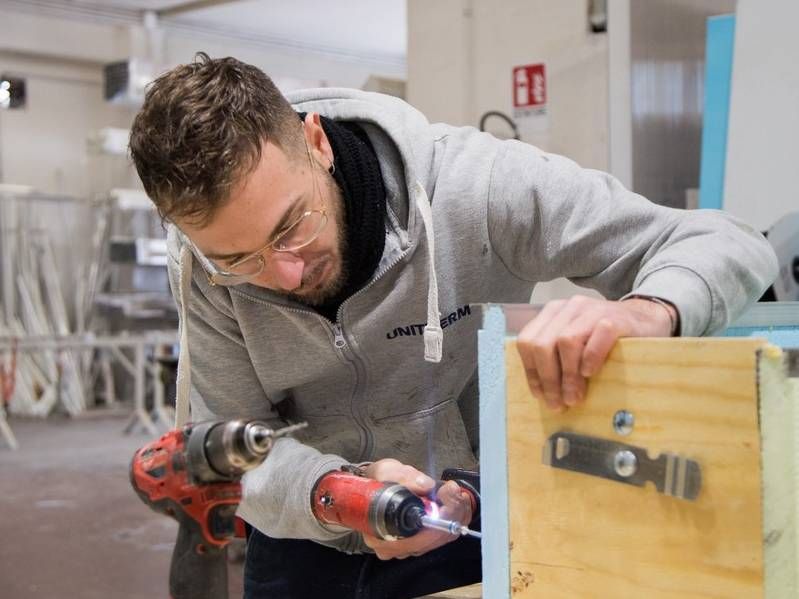 Un uomo sta lavorando un pezzo di legno con un trapano.