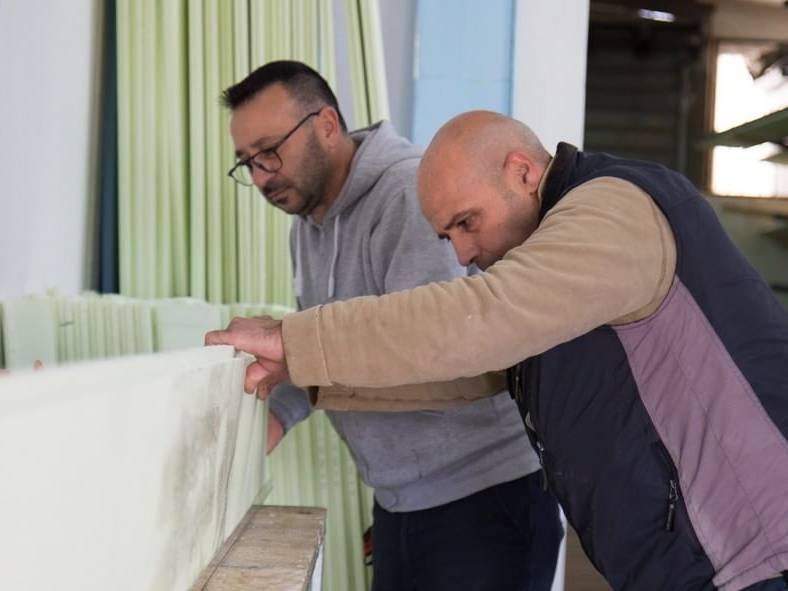 Due uomini stanno lavorando su un pezzo di schiuma in una fabbrica.