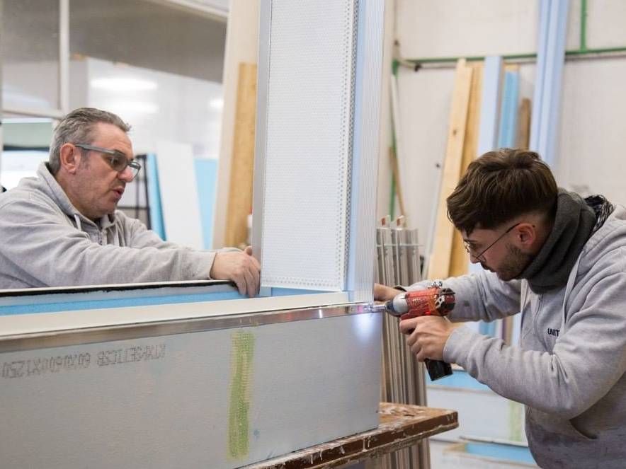 Due uomini stanno lavorando su un pezzo di metallo in una fabbrica.