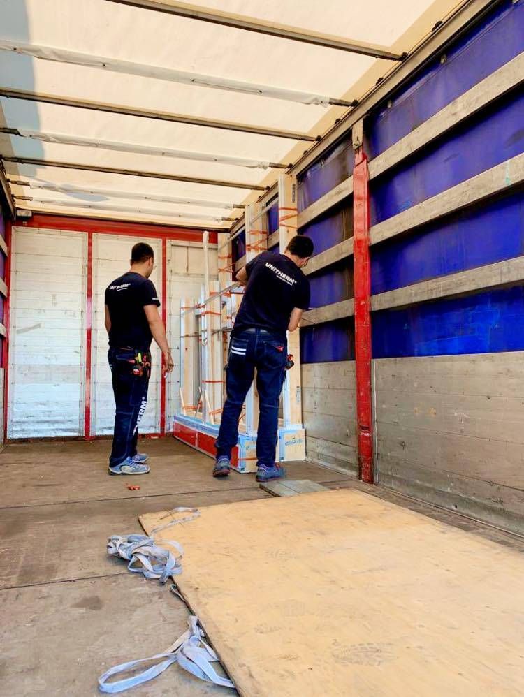 Due uomini sono in piedi sul retro di un camion.