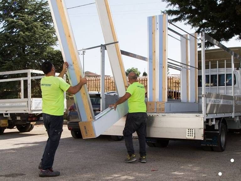 Due uomini con camicie verde neon trasportano un grosso pezzo di legno
