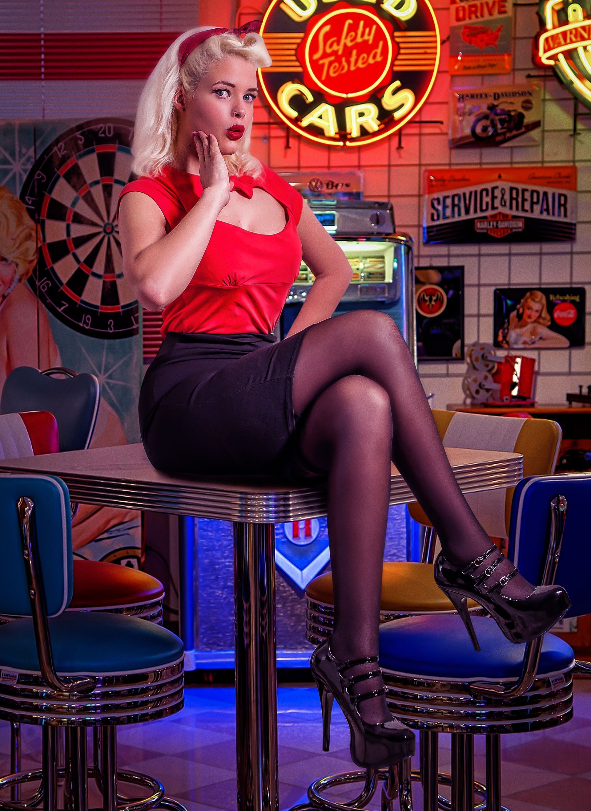 Donna in una tavola calda, con top rosso, gonna nera e tacchi, seduta su uno sgabello.