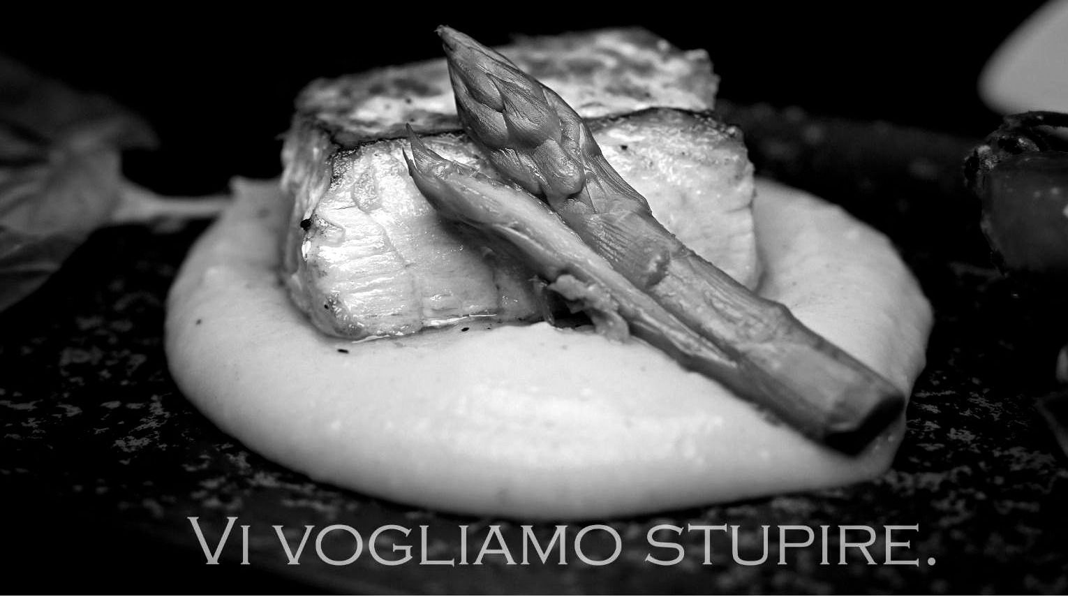 Pesce alla griglia con asparagi su un letto di purè di patate. Foto in bianco e nero.