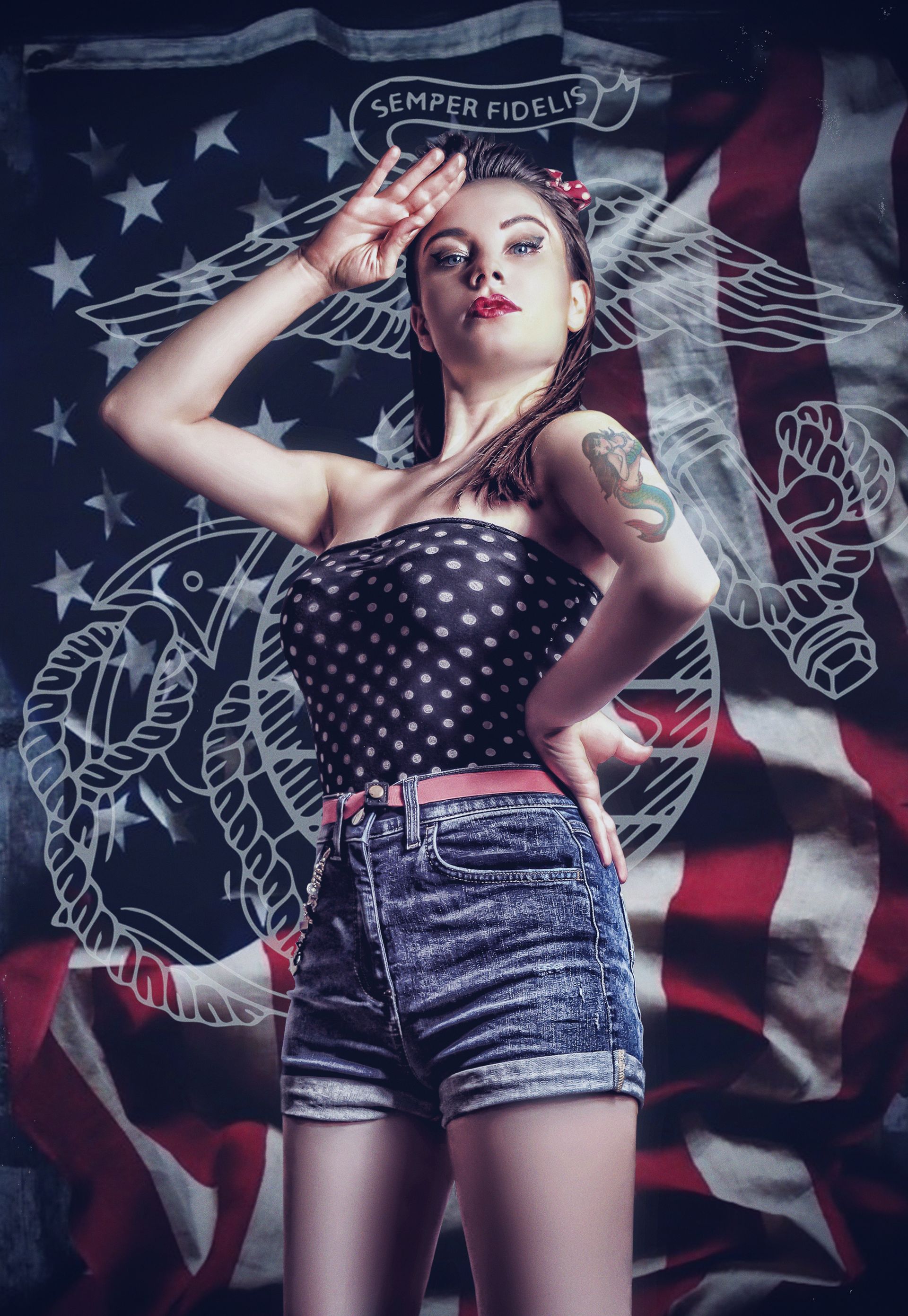 Donna in tenuta da pin-up che saluta davanti a una bandiera americana con il contorno del simbolo dei Marines.