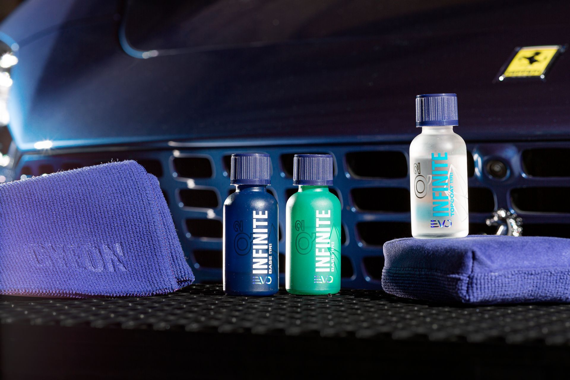 Three bottles of infinite sitting in front of a blue car