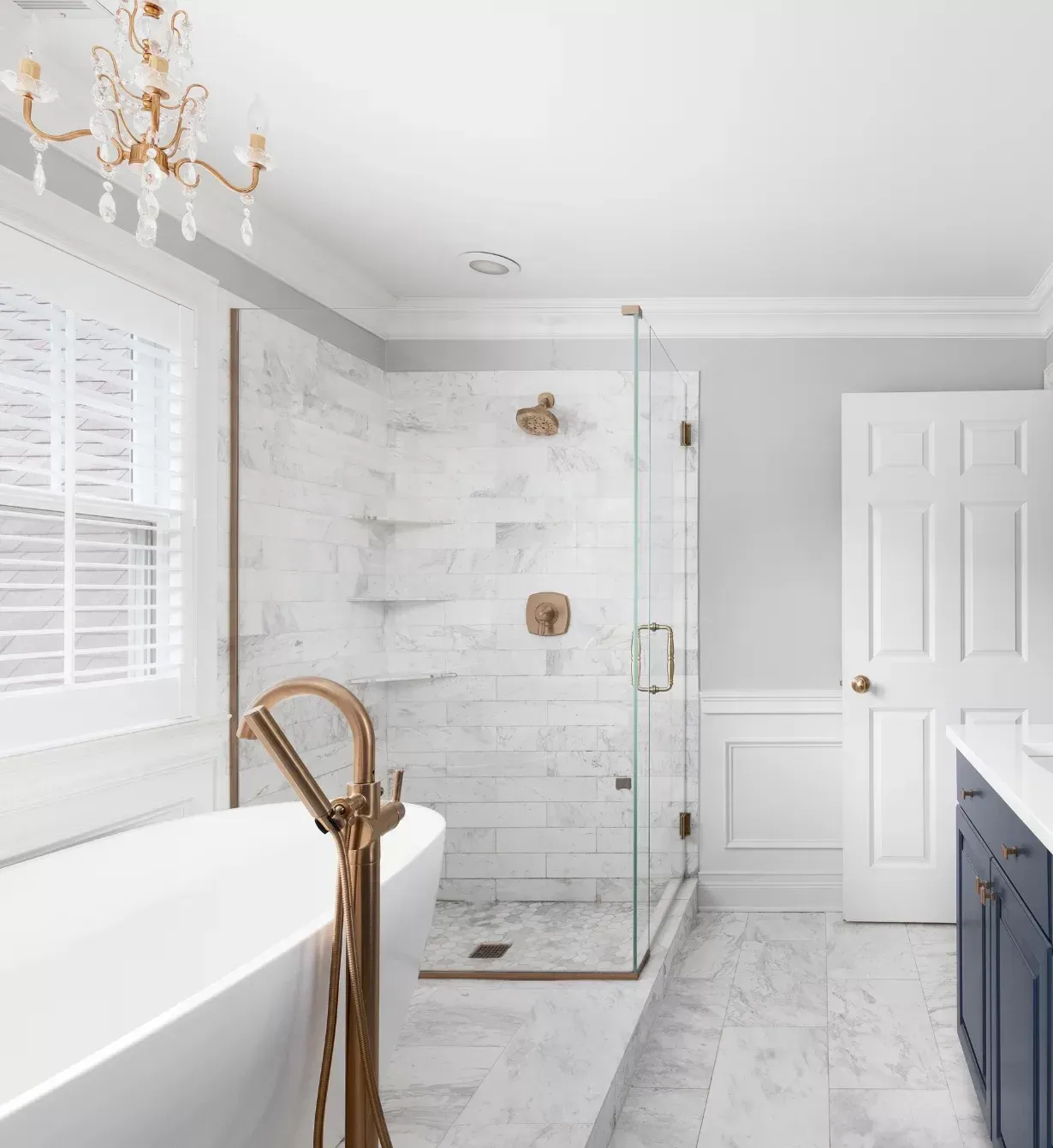 Elegant bathroom with white tub, marble shower, and gold fixtures.