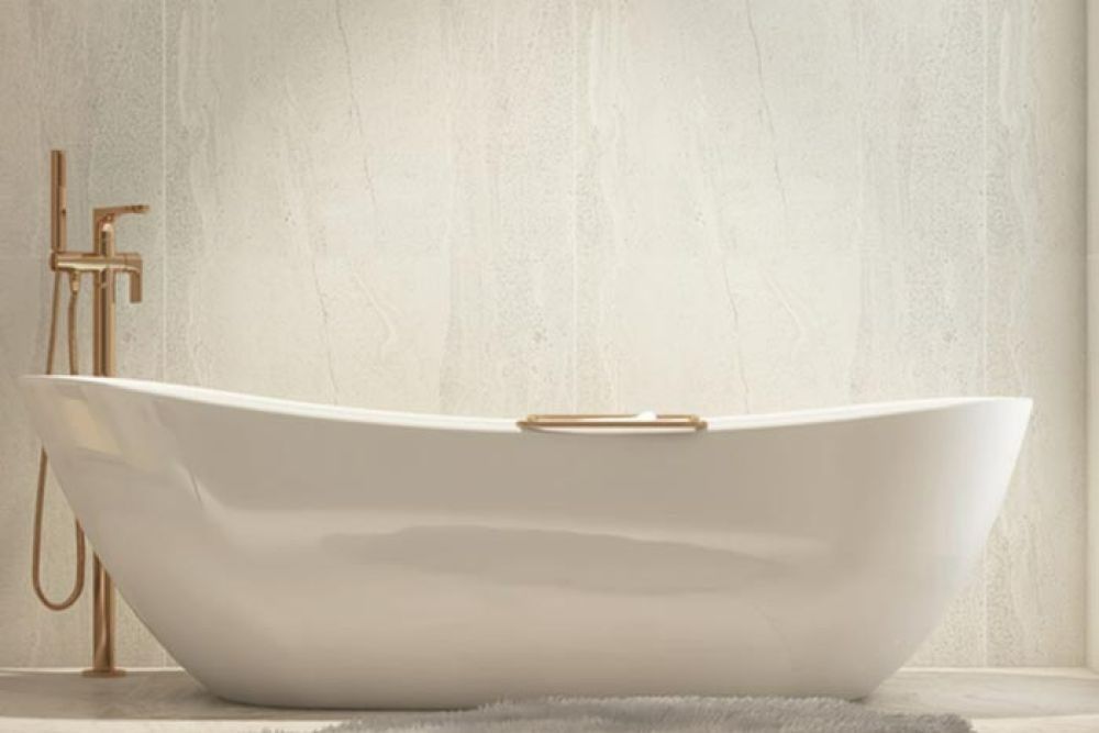 White bathtub with gold fixtures, set against a cream-colored wall.