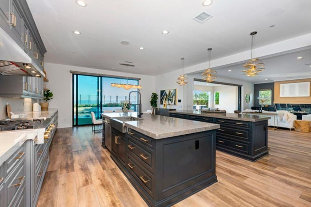 Spacious modern kitchen with gray cabinets, two islands, and a view of an outdoor patio.