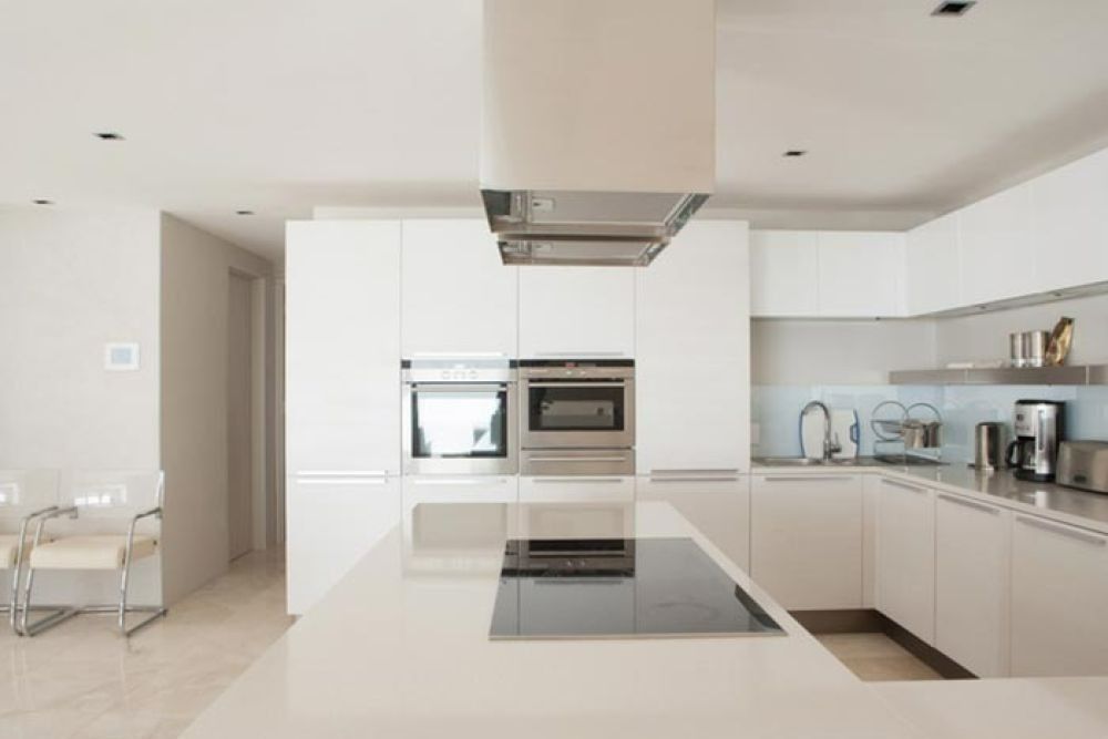 Modern white kitchen with island, stainless steel appliances, and sleek design.