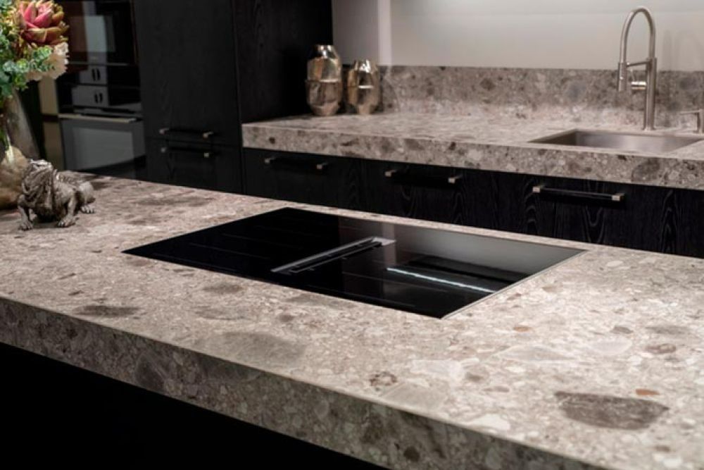Kitchen countertop with integrated cooktop, sink, and cabinets; granite with dark cabinets.