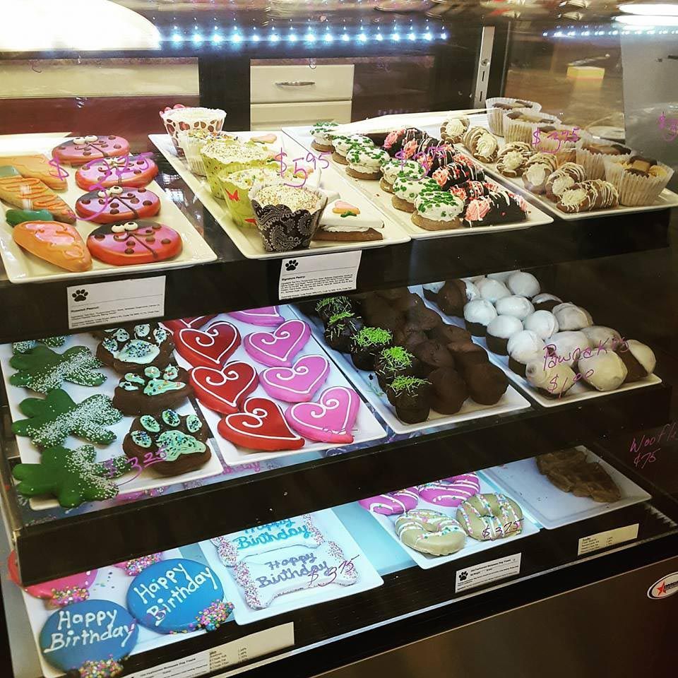 A display case filled with a variety of cupcakes and cookies including one that says happy birthday