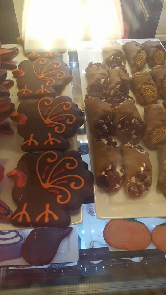 A display case filled with a variety of desserts including cookies and cannoli.