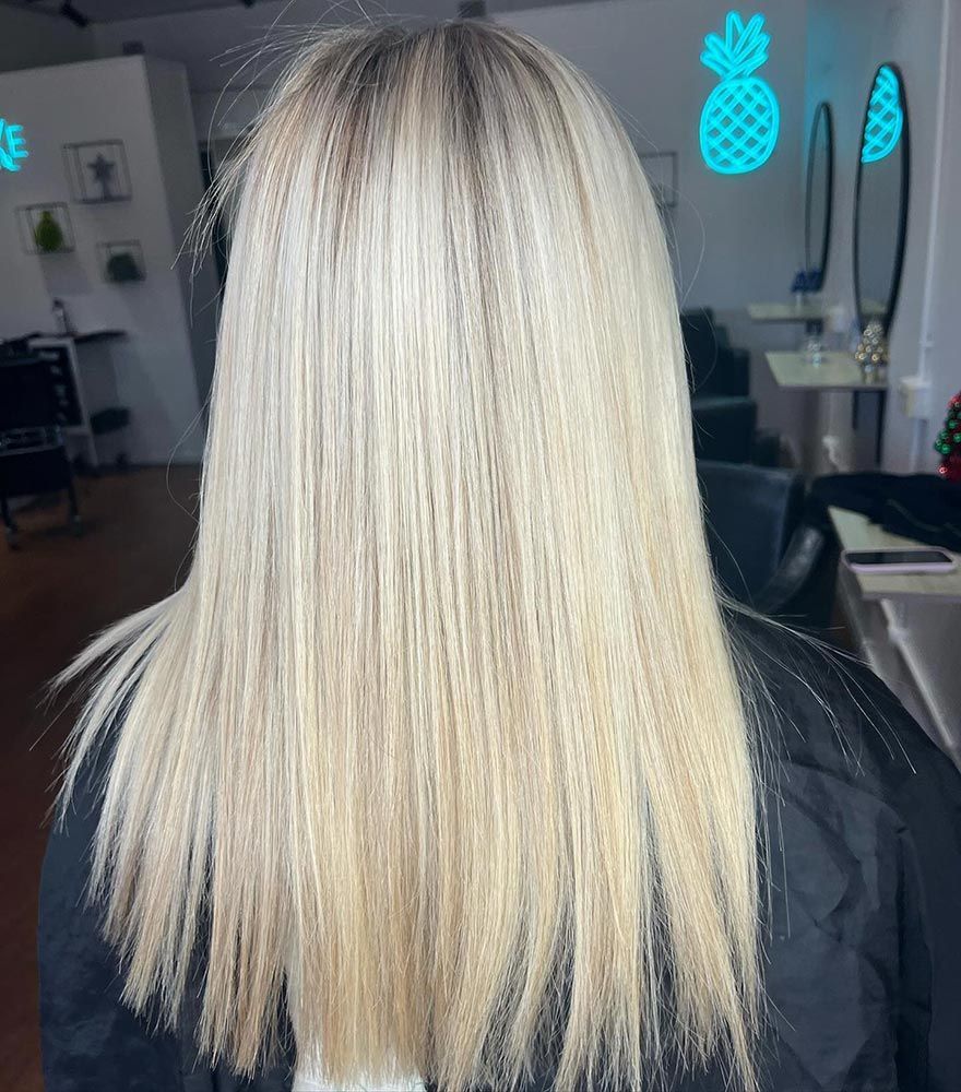 A Woman With Long Blonde Hair is Sitting in a Chair in a Salon — Hairenvy in Ettalong Beach, NSW