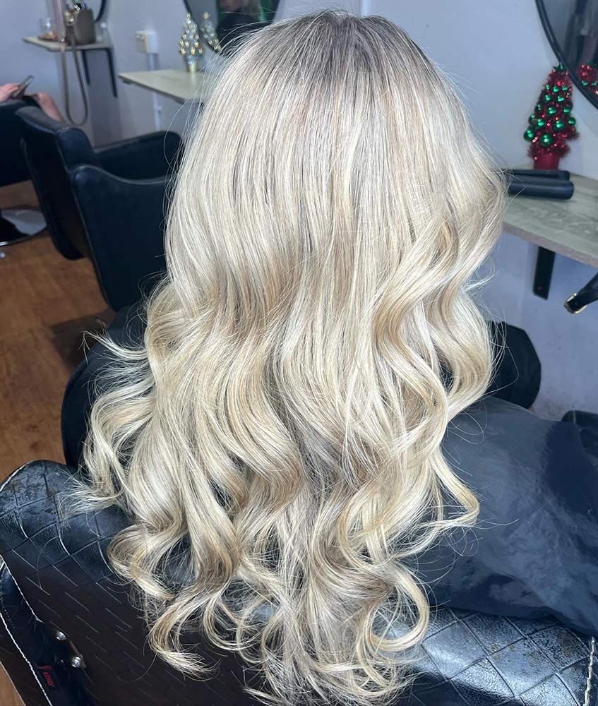 A Woman With Long Blonde Hair is Sitting in a Chair in a Salon — Hairenvy in Ettalong Beach, NSW