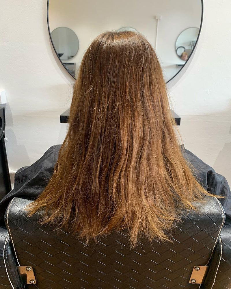 A Woman With Long Hair is Sitting in a Chair in Front of a Mirror — Hairenvy in Ettalong Beach, NSW