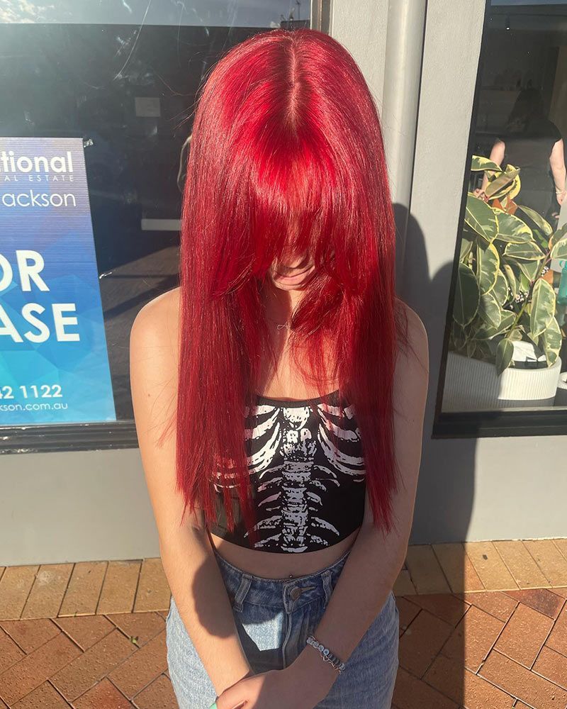 A Woman With Red Hair is Standing in Front of a Store Window — Hairenvy in Ettalong Beach, NSW