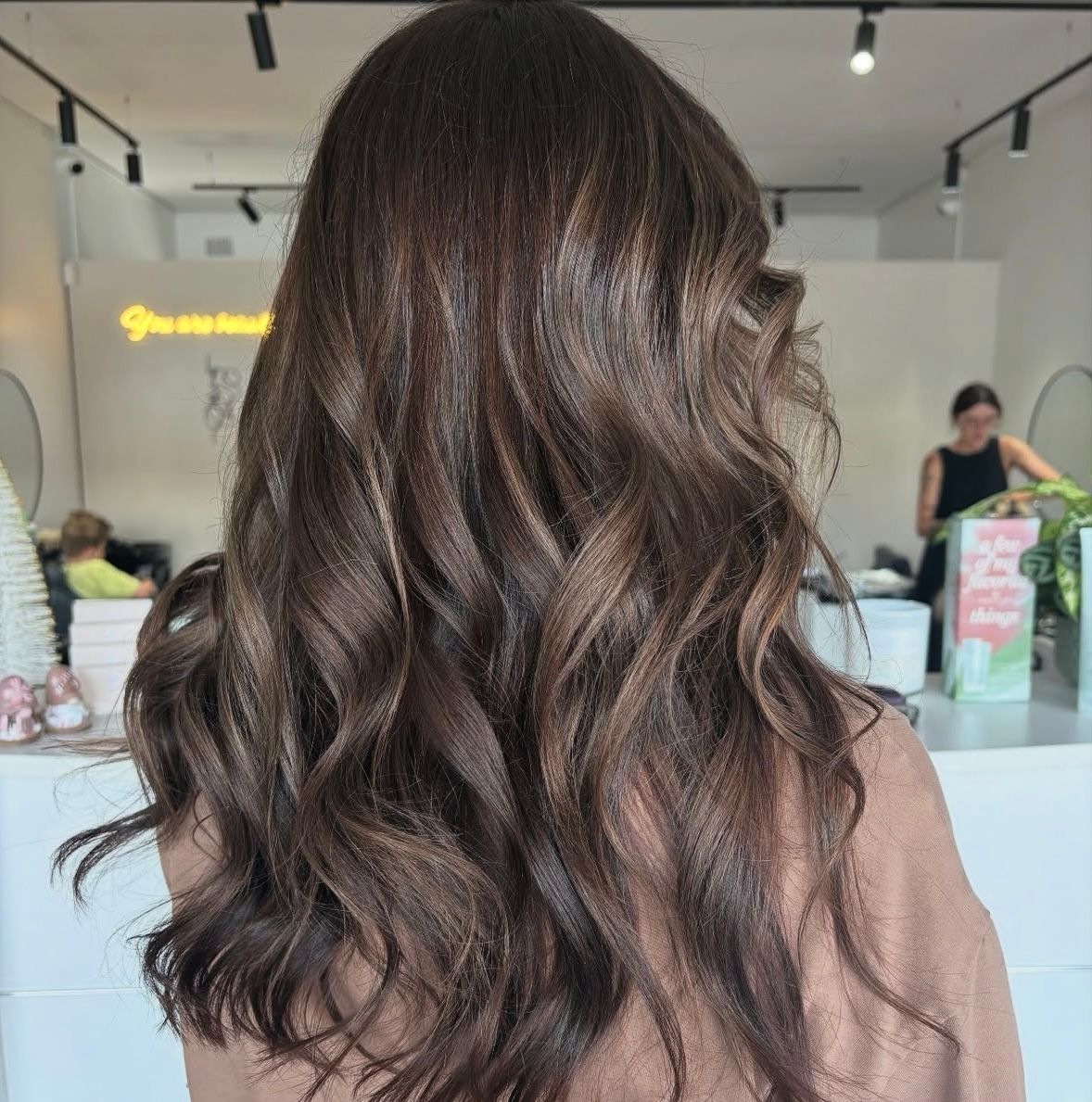 A Woman With Long Brown Hair is standing at a Salon — Hairenvy in Ettalong Beach, NSW