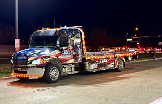 Tow truck decorated with an American flag design at night.