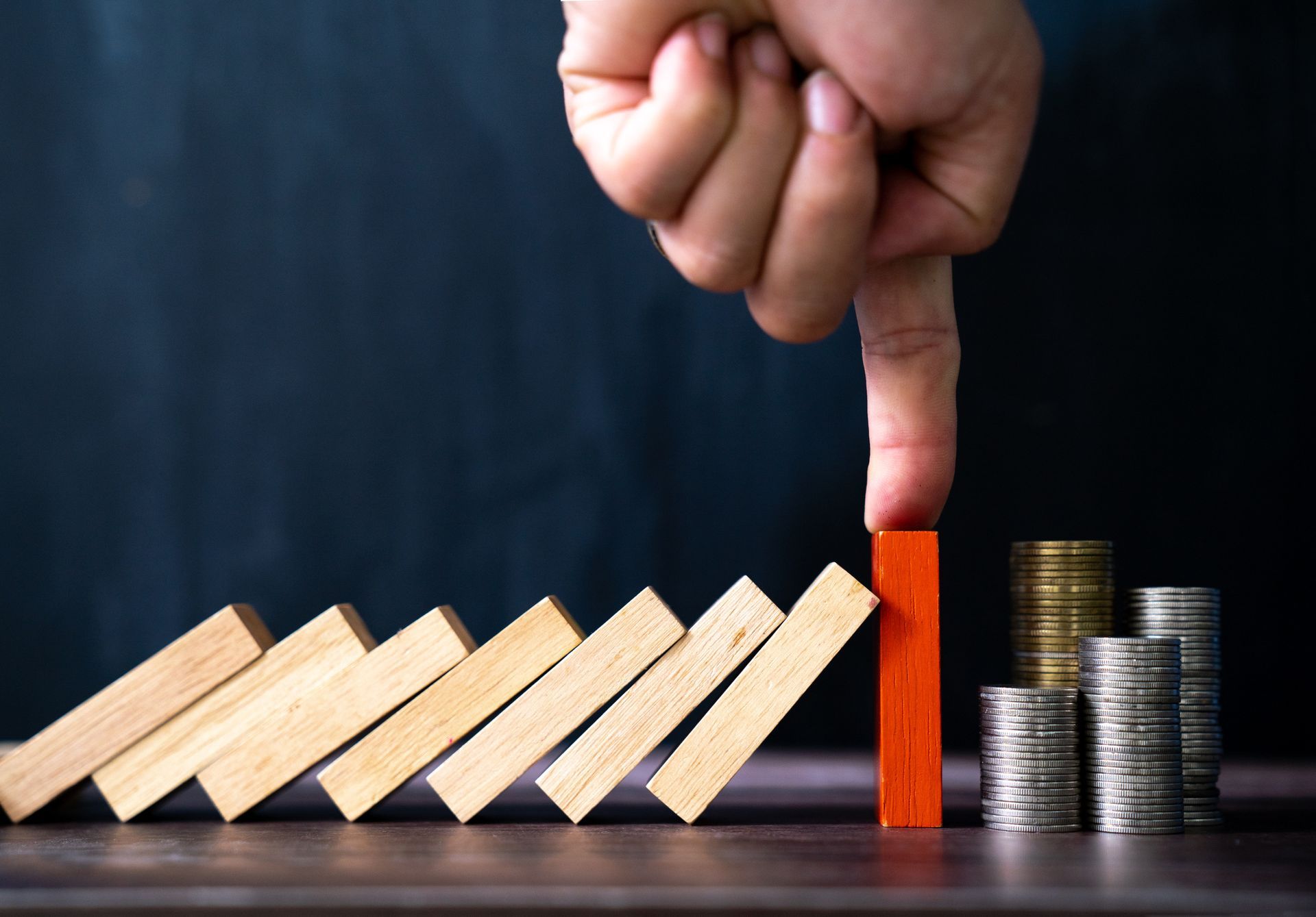 A person is playing a game of dominoes with stacks of coins in the background.