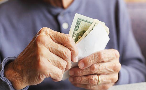 An elderly woman is holding a stack of money in her hands.