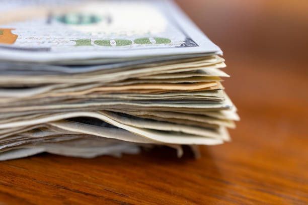 A stack of money is sitting on a wooden table.